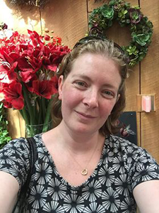 Image of Emily Lewis with flowers behind her.