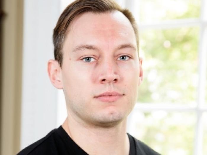 Headshot of Alex Pyron in front of a window